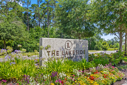 The Lakeside monument sign, framed by vibrant flowers and lush tropical greenery, welcomes residents and visitors to this beautiful Fernandina Beach FL senior living community.