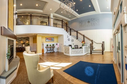 High ceiling foyer with wooden floors, a reception area, and a staircase