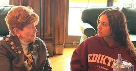 A resident and a young student share a meaningful conversation, reflecting the intergenerational connections fostered at Arbor Terrace Monmouth, a senior living community in Shrewsbury, NJ.